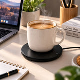 Black USB mug warmer keeping a coffee mug warm beside a laptop